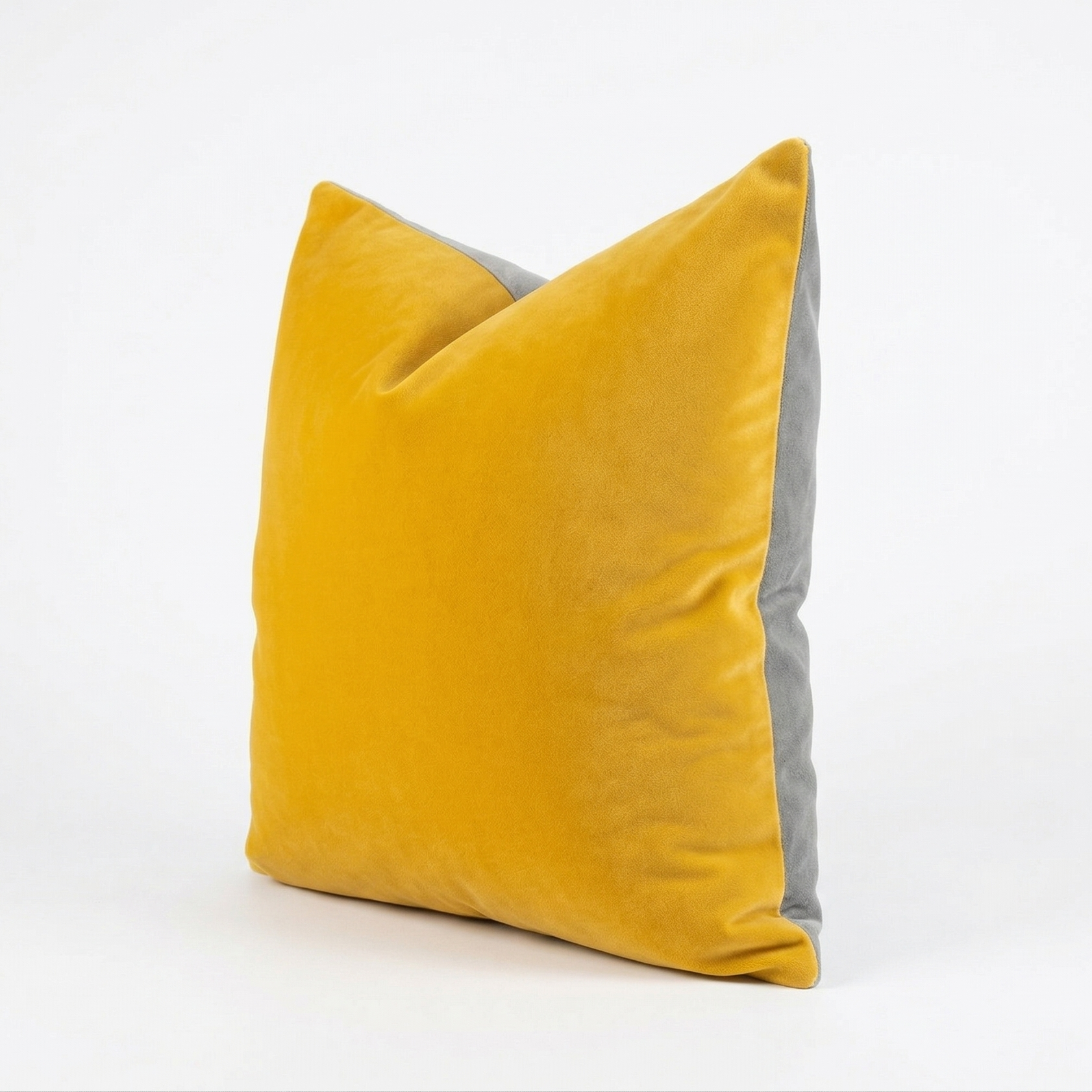 Yellow velvet pillow with gray back on a white background