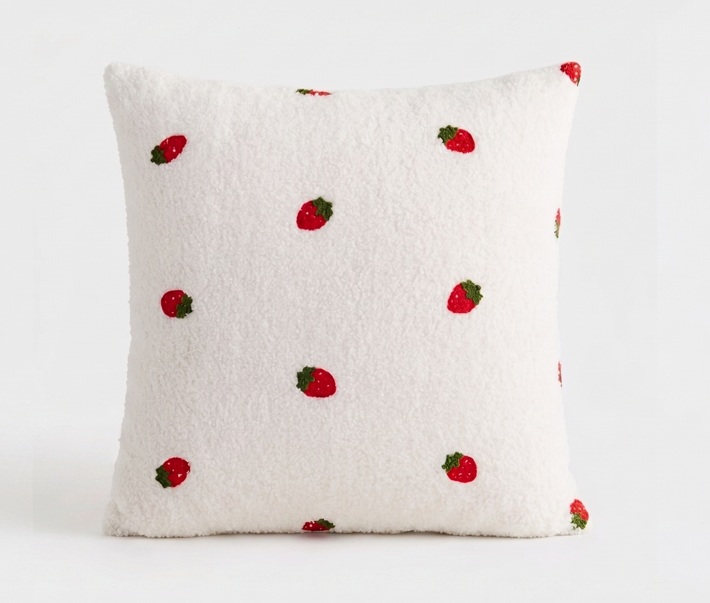 A square white sherpa throw pillow with a pattern of embroidered red strawberries, shown against a plain white background. Pillow cover has a zipper and can be removed and is washable. Insert sold separately. 