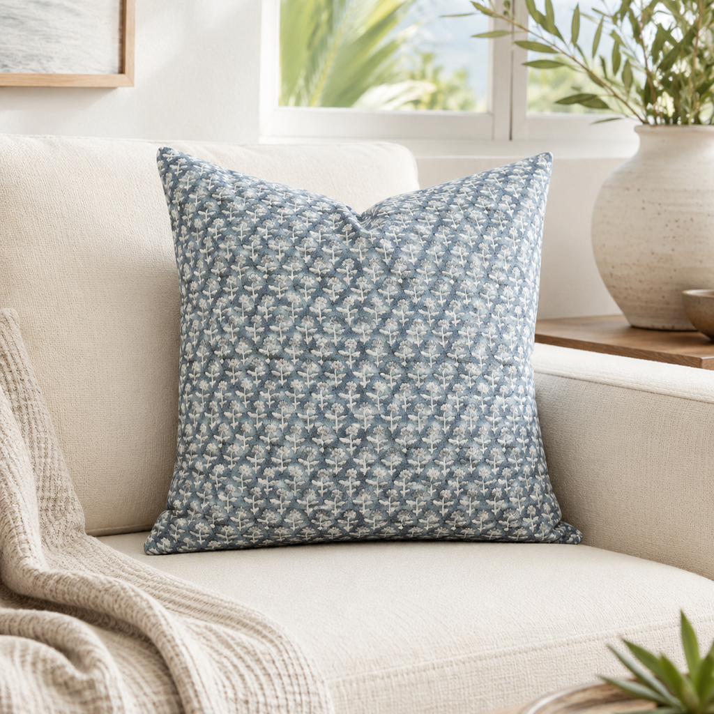 Blue floral patterned pillow on a beige couch with a neutral background