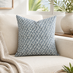 Blue floral patterned pillow on a beige couch with a neutral background