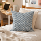 Blue patterned pillow on a beige sofa with a desk and chair in the background. Decorative pillows feature removable covers with zippers 20x20.