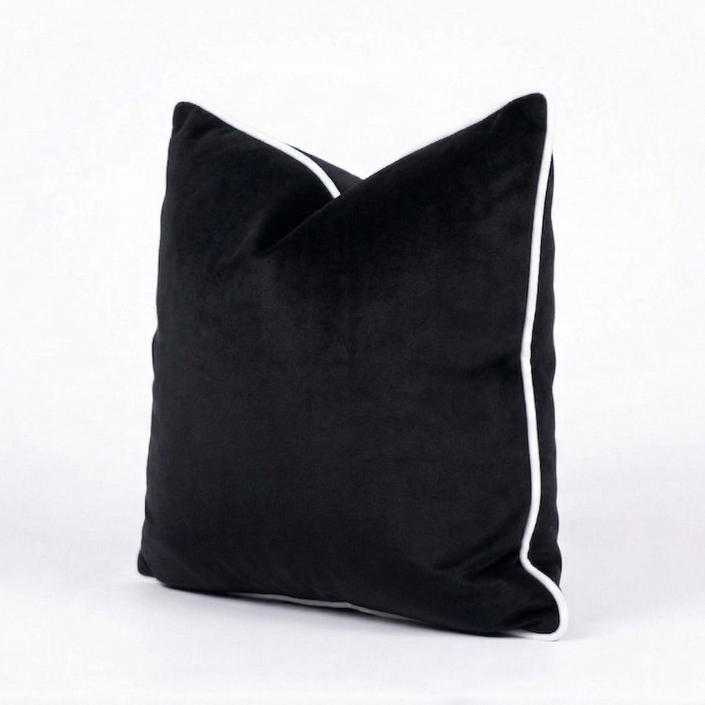 Black velvet throw pillow cover with white trim on a white background