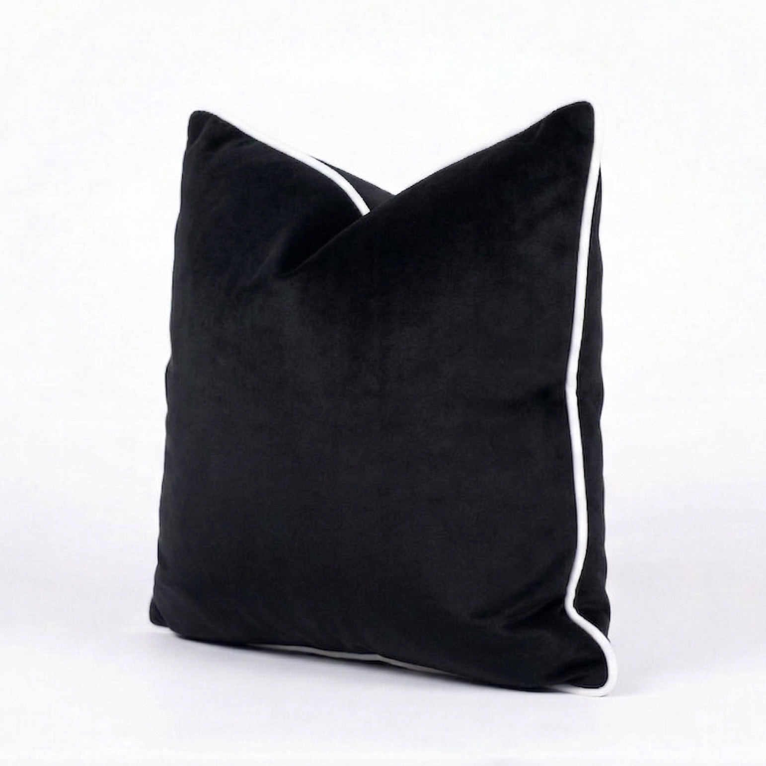 Black velvet throw pillow cover with white trim on a white background