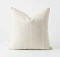 Beige pillow with white decorative stitching on a white background