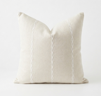 Beige pillow with white decorative stitching on a white background