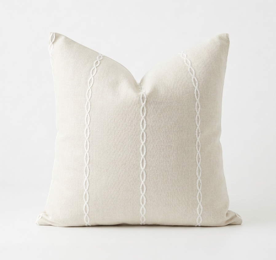 Beige pillow with white decorative stitching on a white background