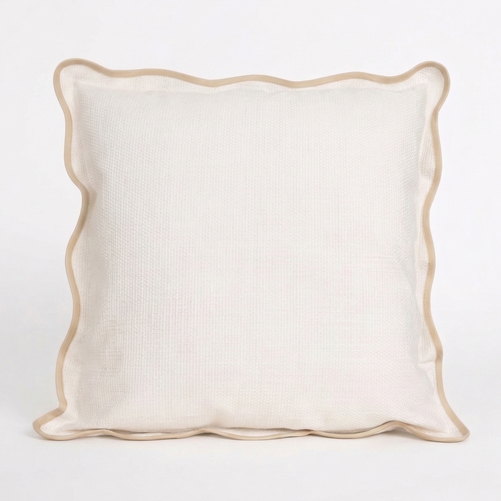 White pillow with beige, scalloped trim on a white background