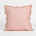 Pink pillow with scalloped edge on a white background