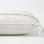 Textured pillow with tassel on a white background. Pillow cover features a zipper for easy removal.
