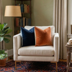 Beige armchair with blue and orange velvet pillows in a cozy living room setting.