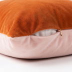 Two-toned pillow with orange top and pink bottom on a white background. Featuring side zipper to easily remove pillow cover.