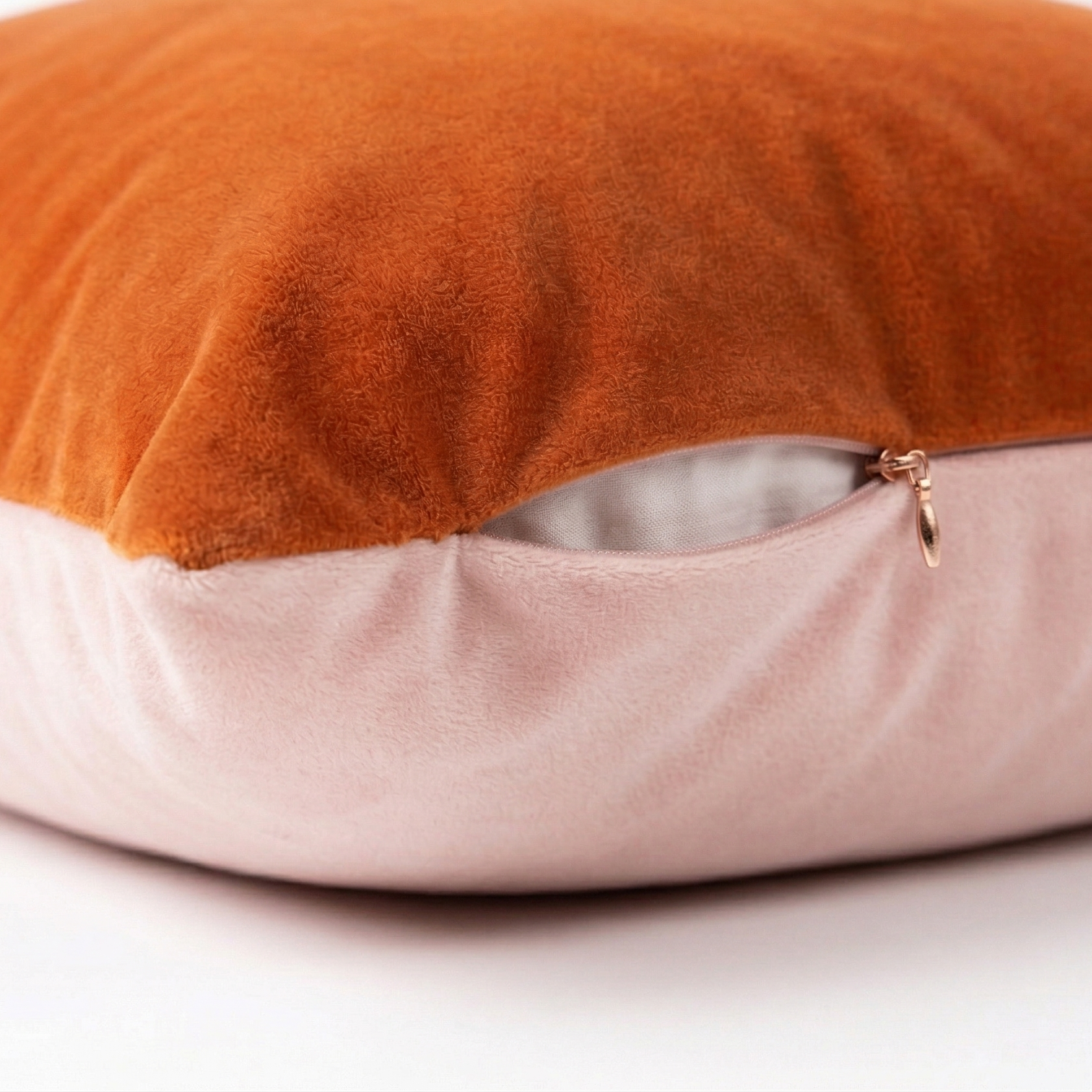 Two-toned pillow with orange top and pink bottom on a white background. Featuring side zipper to easily remove pillow cover.